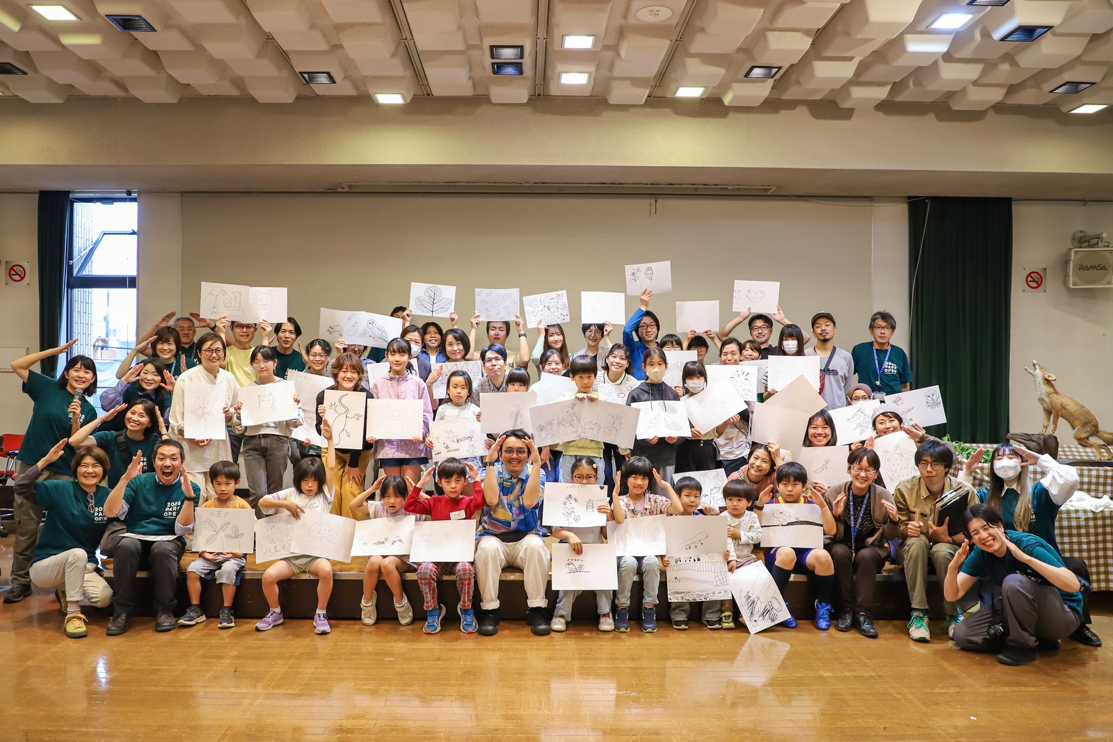 子どもたちが描いた絵を手にした集合写真